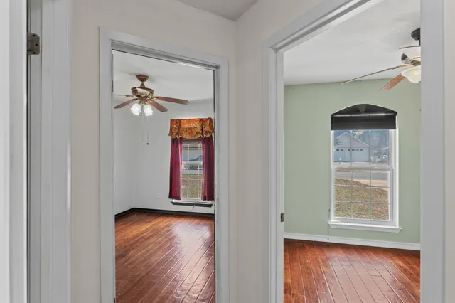 an empty room with wooden floor chandelier fan and windows