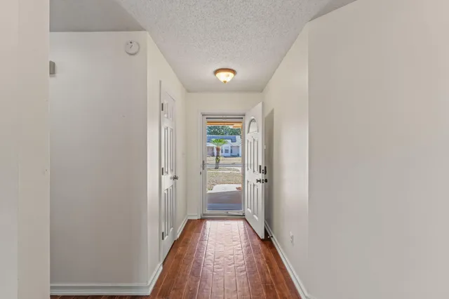 a view of a hallway with wooden floor and a bathroom
