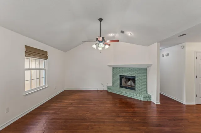 a view of a livingroom with wooden floor a fireplace and windows