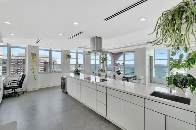 a large white kitchen with a large window and stainless steel appliances
