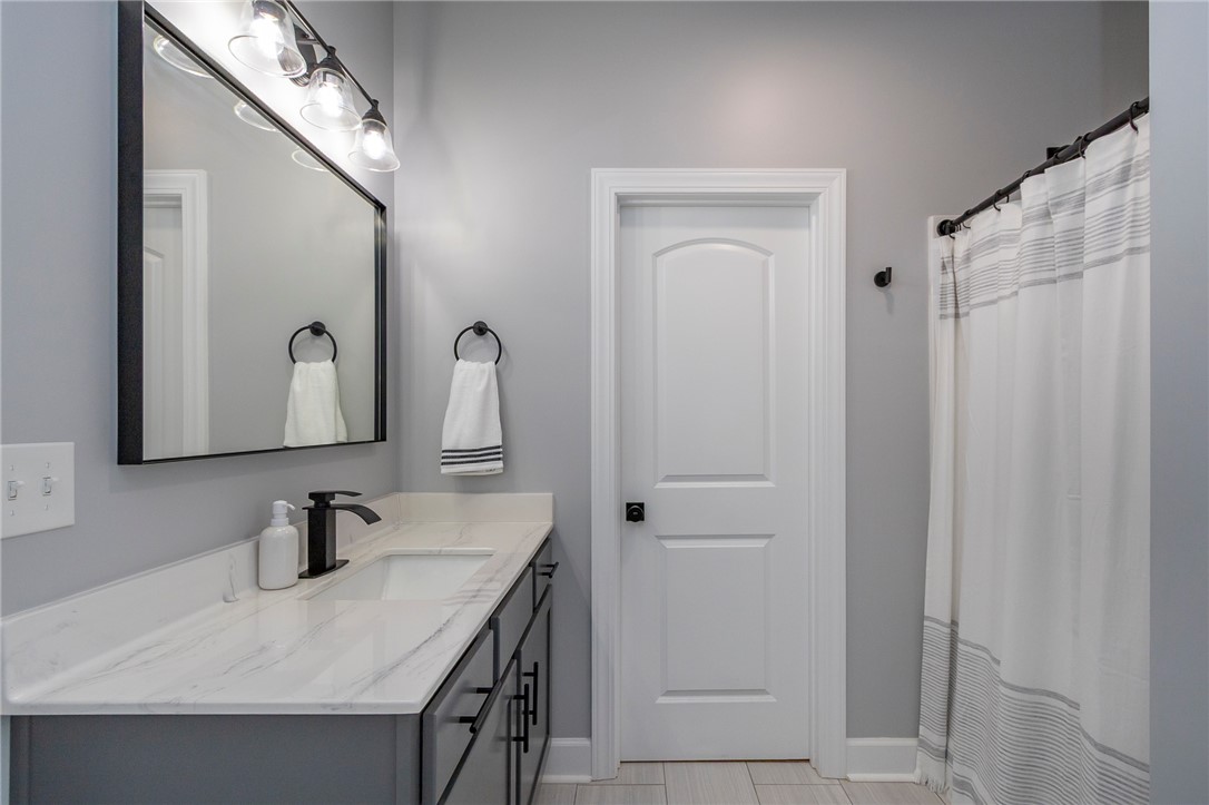 3080 McGee Road Iva, SC 29655 - Photo 34 of 49 Modern bath features a single vanity with stone counters and a shower with a privacy curtain.