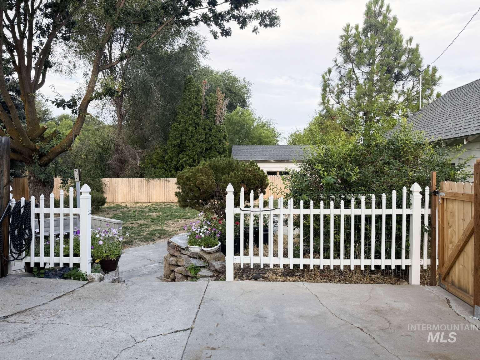 1158 South Powerline Road Nampa, ID 83686 - Photo 8 of 46 Picket fence entry with a wood gate, concrete driveway, and mature landscaping