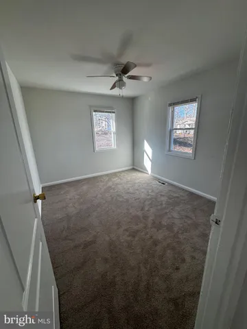 an empty room with windows and fan view
