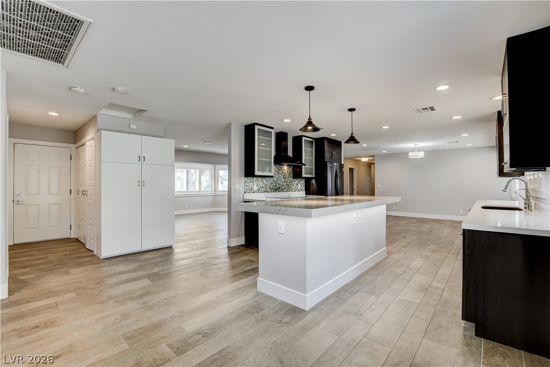 4207 Ridgecrest Drive Las Vegas, NV 89121 - Photo 9 of 27 Kitchen with glass fronted cabinets, decorative backsplash, tile floors, a center island, and pendant lighting