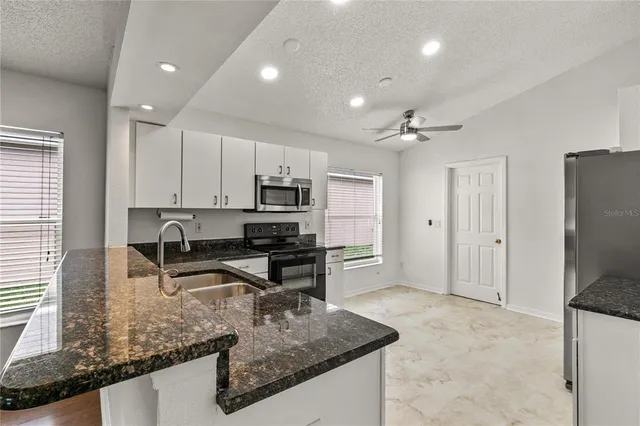 a kitchen with kitchen island granite countertop a stove refrigerator and microwave