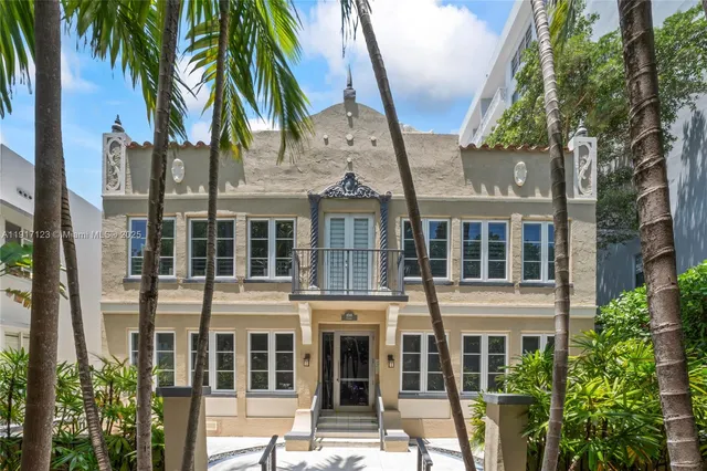 a front view of a building with glass windows and palm trees