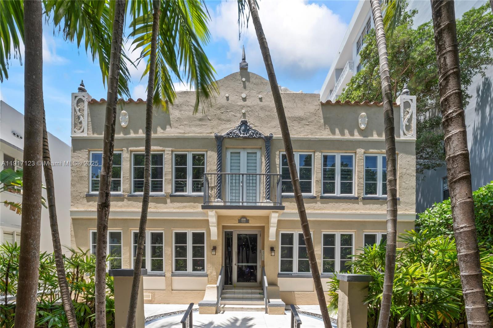 a front view of a building with glass windows and palm trees