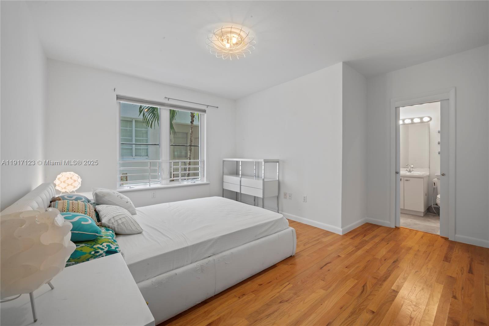 1018 Meridian Avenue, Unit 5 Miami Beach, FL 33139 - Photo 17 of 18 a bedroom with a bed table flowerpot and window