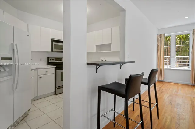 a kitchen with stainless steel appliances kitchen island granite countertop a table chairs and a refrigerator