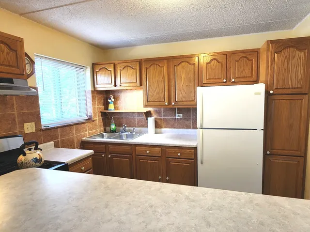 a kitchen with stainless steel appliances granite countertop a refrigerator and a sink