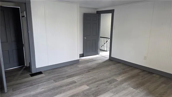 an empty room with wooden floor and entrance