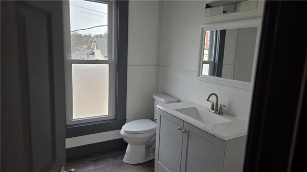 a bathroom with a toilet sink vanity and windows