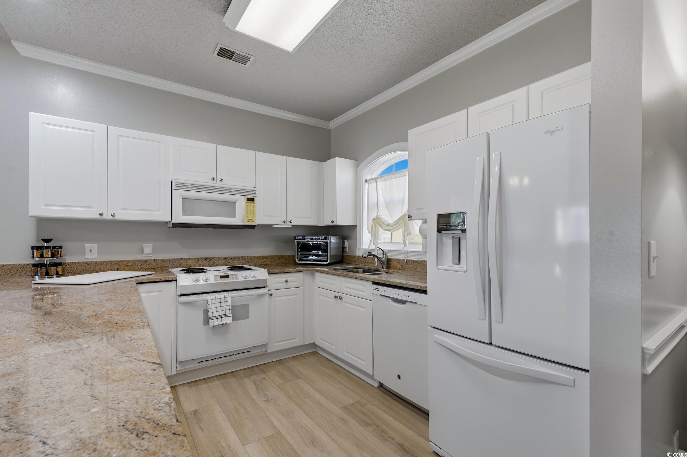 4839 Carnation Circle, Unit 305 Myrtle Beach, SC 29577 - Photo 3 of 24 Kitchen with white appliances, crown molding, white cabinetry, a textured ceiling, and light wood-style flooring