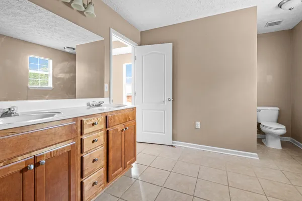 a spacious bathroom with a double vanity sink a toilet and a mirror