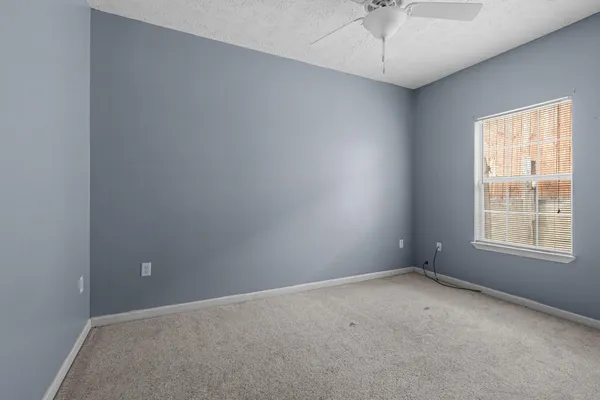 an empty room with a window and a fan
