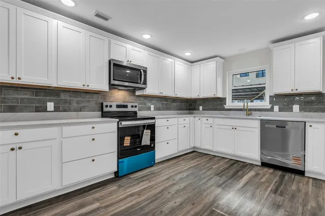 a kitchen with granite countertop a stove top oven a sink dishwasher and a refrigerator with wooden floor