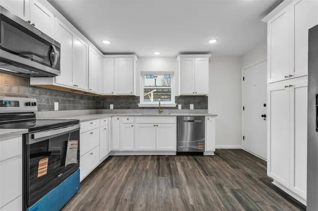 a kitchen with granite countertop white cabinets and stainless steel appliances