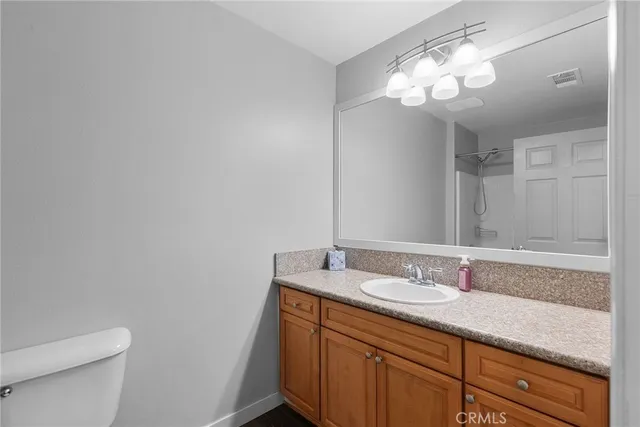a bathroom with a granite countertop sink a toilet and a mirror