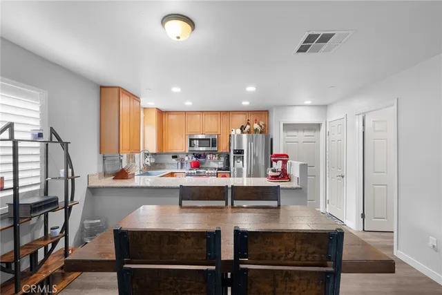 a room with stainless steel appliances kitchen island granite countertop a table chairs and a refrigerator