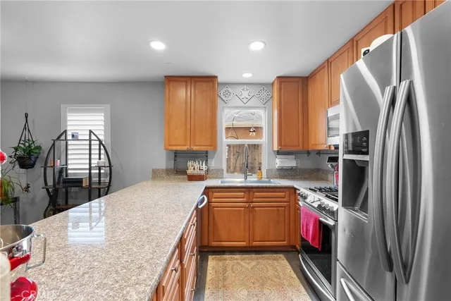 a kitchen with kitchen island granite countertop a sink a counter top space stainless steel appliances and cabinets
