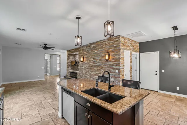 a kitchen with granite countertop a stove a sink dishwasher a refrigerator with a dining table and chairs