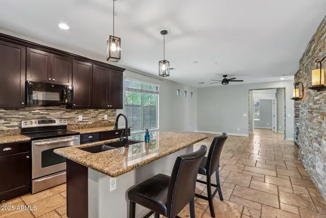 a kitchen with stainless steel appliances kitchen island granite countertop a refrigerator a stove a kitchen island a dining table and chairs