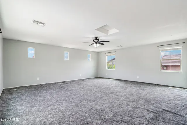 an empty room with windows and ceiling fan