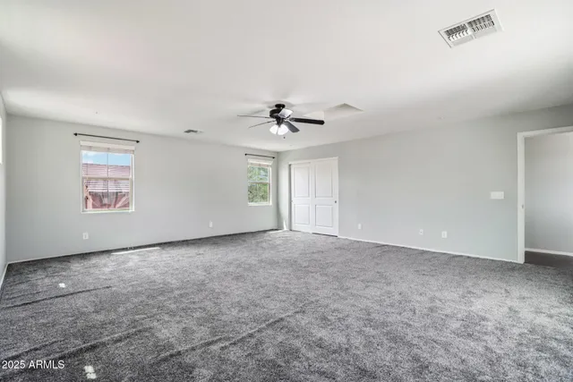 an empty room with windows and ceiling fan