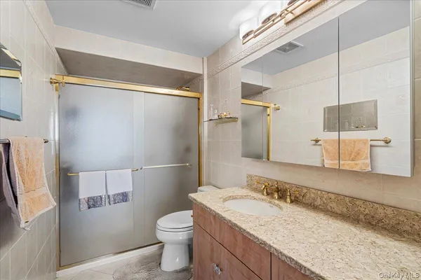 a bathroom with a granite countertop sink toilet and shower