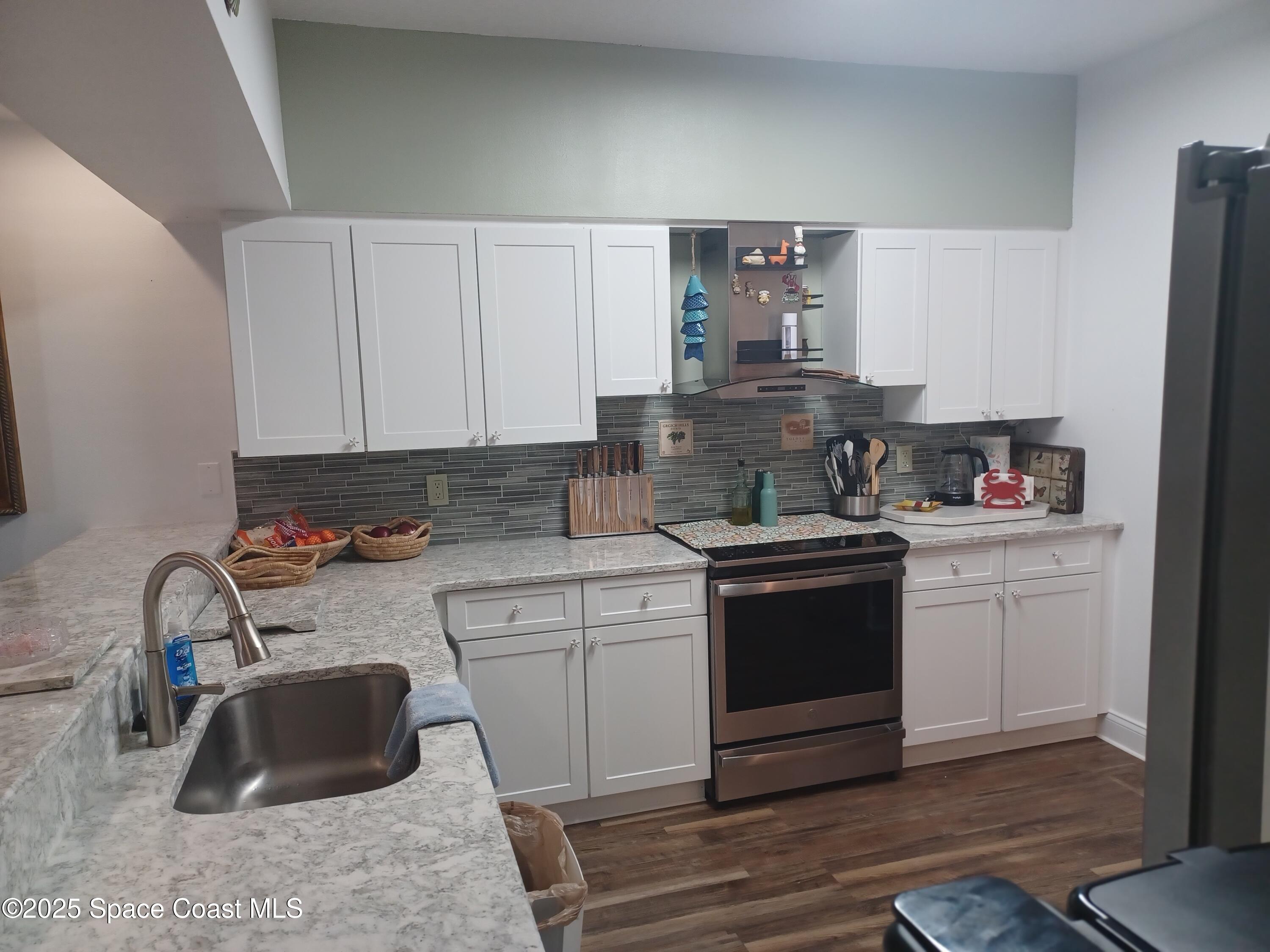 105 Pulsipher Avenue, Unit 403 Cocoa Beach, FL 32931 - Photo 5 of 15 a kitchen with sink a stove and cabinets