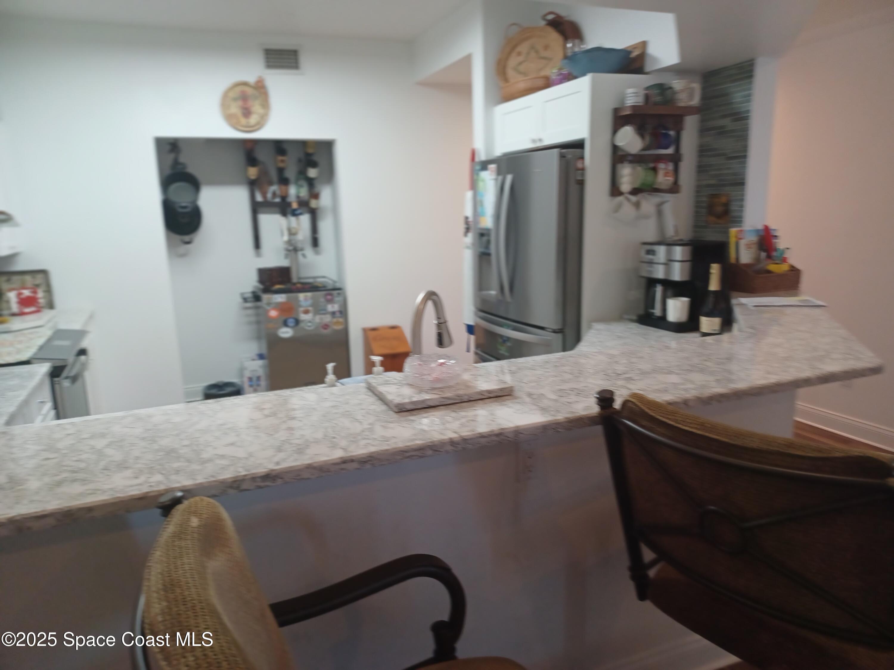 105 Pulsipher Avenue, Unit 403 Cocoa Beach, FL 32931 - Photo 7 of 15 a kitchen with a sink and a refrigerator