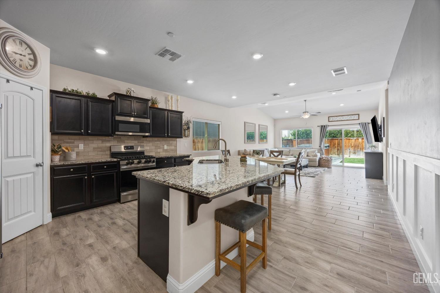 Undisclosed Address Shafter, CA 93263 - Photo 9 of 43 a kitchen with stainless steel appliances kitchen island granite countertop a stove top oven a sink a dining table and chairs