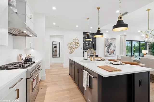 a kitchen with a sink a stove and chairs with wooden floor