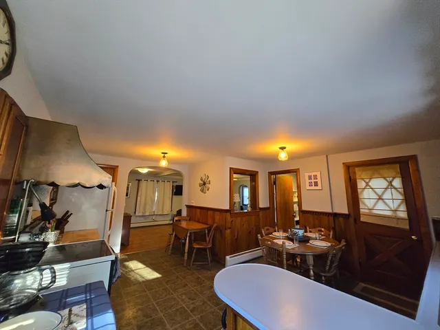 a kitchen with stainless steel appliances a refrigerator a stove a sink a dining table and chairs with wooden floor