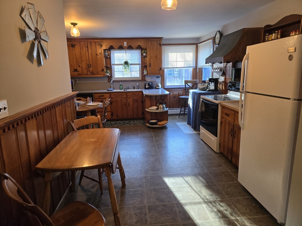 14 Parsons Street, Unit 2 Northampton, MA 01060 - Photo 17 of 28 a kitchen with stainless steel appliances a refrigerator a stove a sink a dining table and chairs with wooden floor