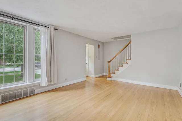 a view of an empty room with wooden floor and windows