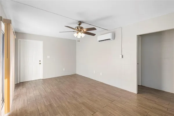 an empty room with wooden floor fan and windows