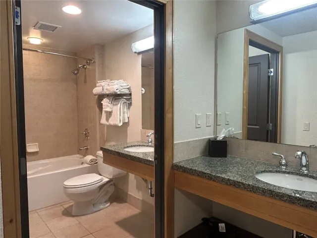 a bathroom with a granite countertop sink toilet a mirror and shower