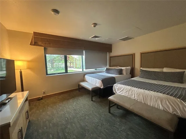 a spacious bedroom with two beds and a window
