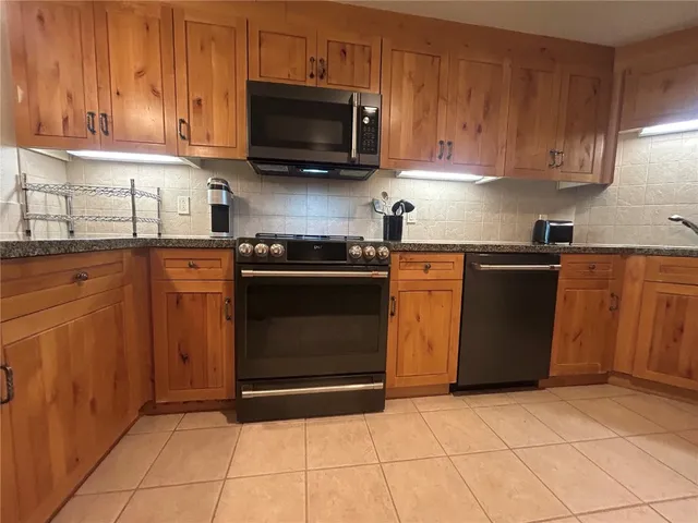 a kitchen with granite countertop a stove top oven microwave and cabinets