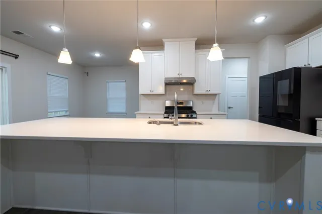 a large white kitchen with kitchen island a sink wooden floor and stainless steel appliances