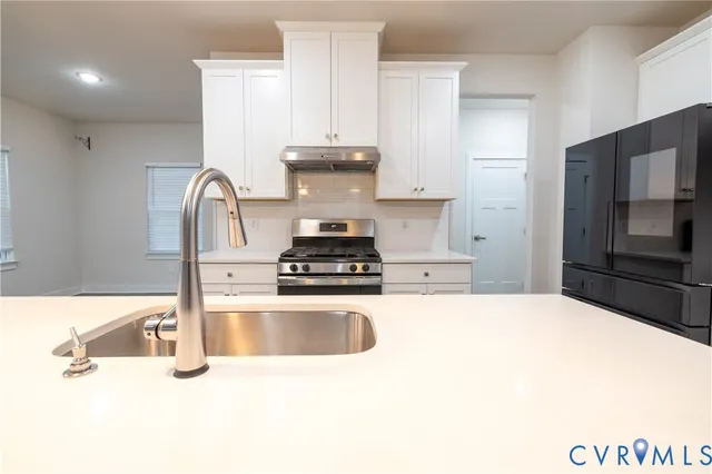 a large white kitchen with kitchen island a sink wooden floor and stainless steel appliances
