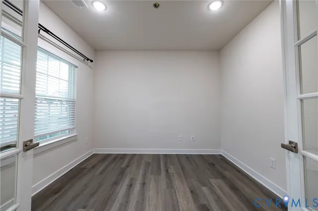 a view of an empty room with wooden floor and a window