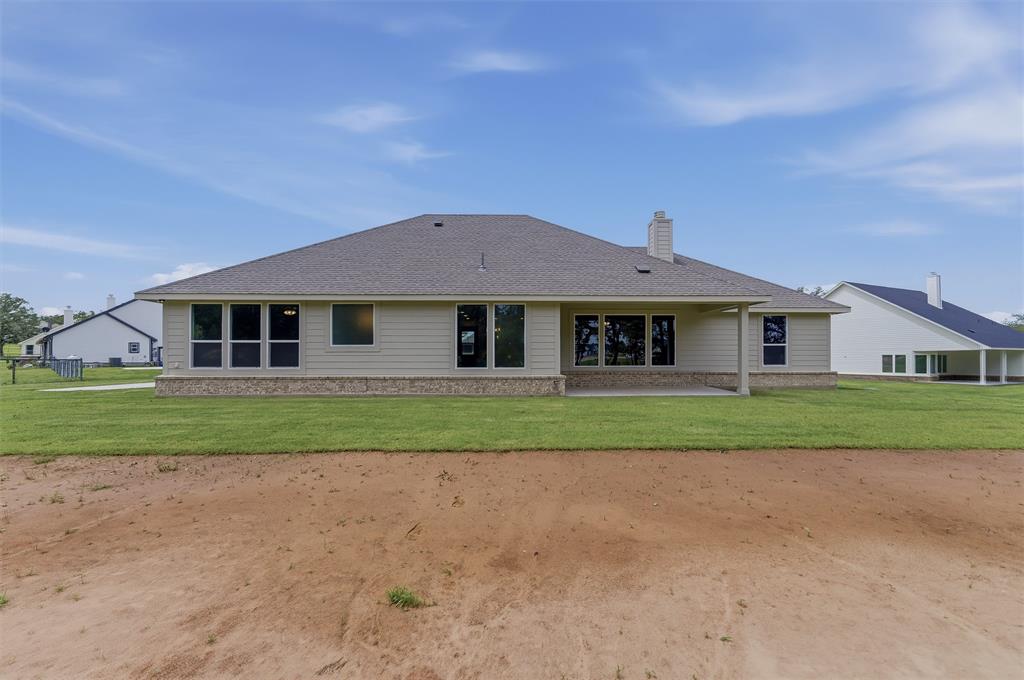 156 Oak Grv Way Springtown, TX 76082 - Photo 23 of 25 Rear exterior featuring a covered patio, multiple large windows, light-colored siding, and a stone foundation accent