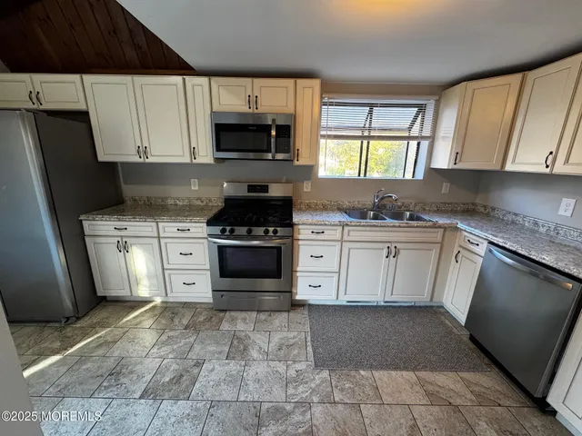 a kitchen with stainless steel appliances granite countertop a refrigerator a stove a sink and a microwave