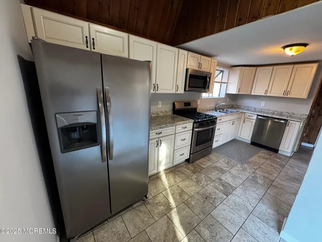 a kitchen with a sink a stove top oven a refrigerator and cabinets