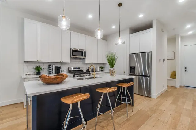 a kitchen with stainless steel appliances granite countertop a stove a refrigerator a sink a dining table and chairs