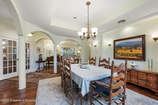 a view of a dining room with furniture a chandelier and wooden floor