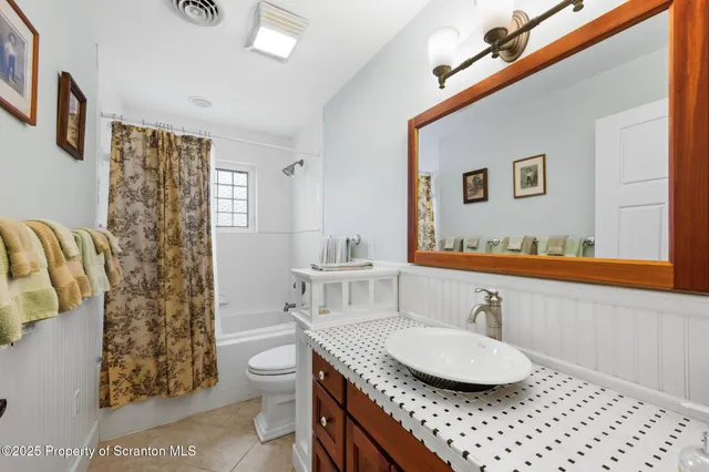 a bathroom with a granite countertop sink a mirror a toilet and shower