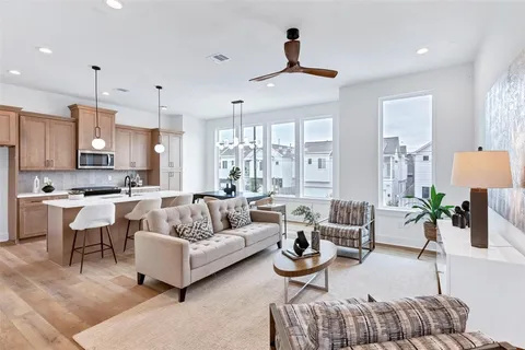 a living room with furniture kitchen view and a large window